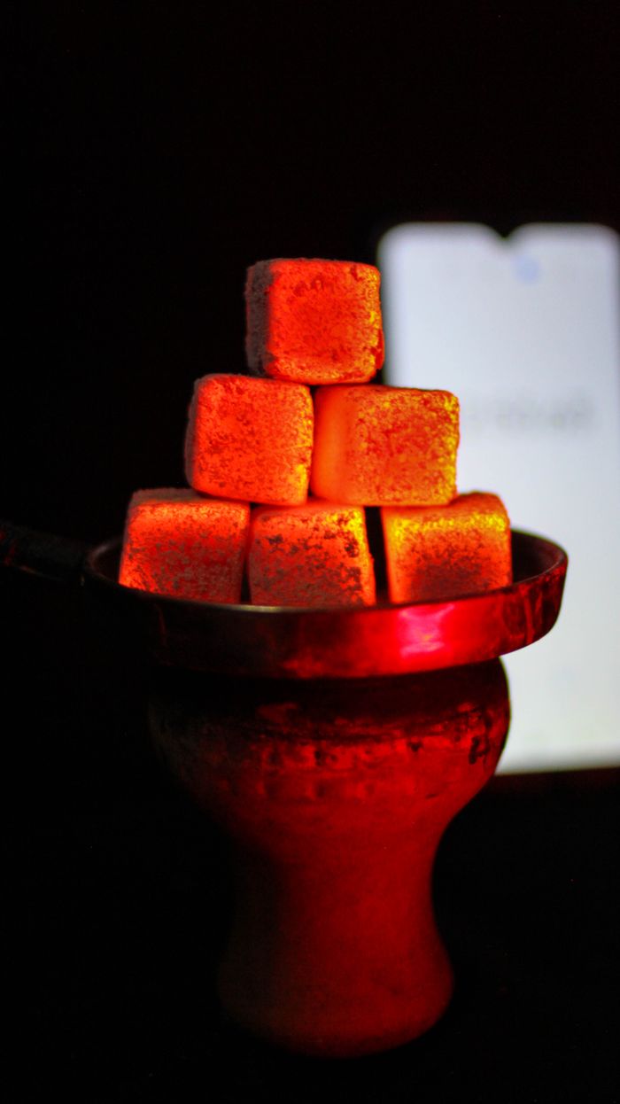 Mastering the First Impression: Your intriguing post title goes here A close-up photo of glowing charcoal cubes stacked on a hookah bowl, emitting vibrant red heat.