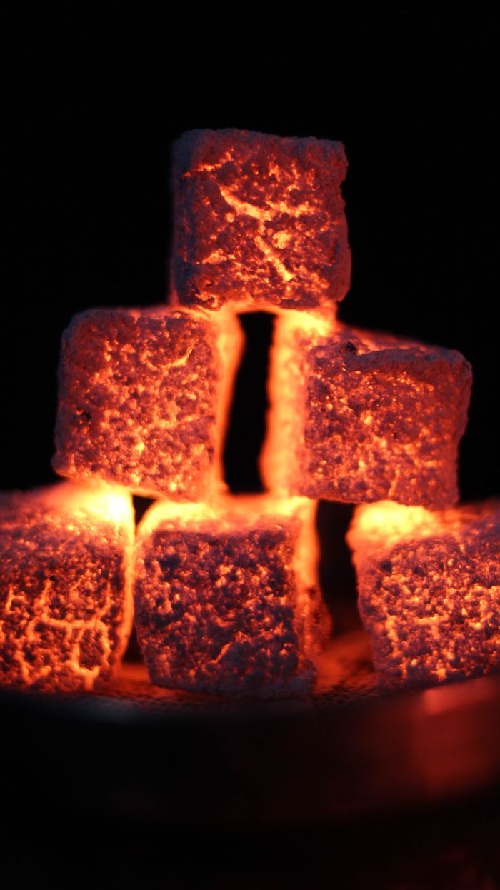 About Close-up of glowing charcoal cubes stacked against a dark background, showcasing heat and texture.